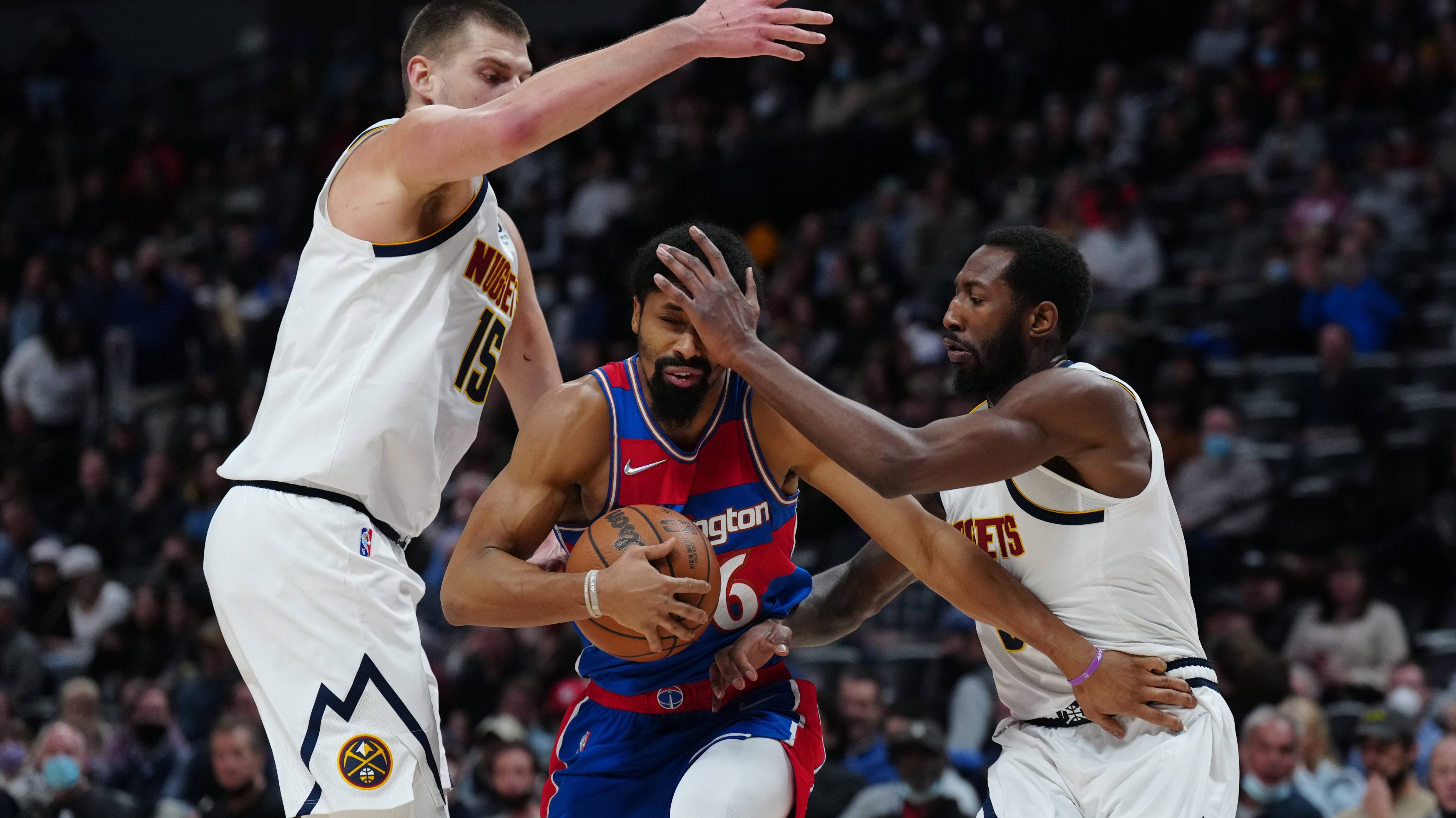 Spencer Dinwiddie attempts to evade a pair of Nuggets defenders