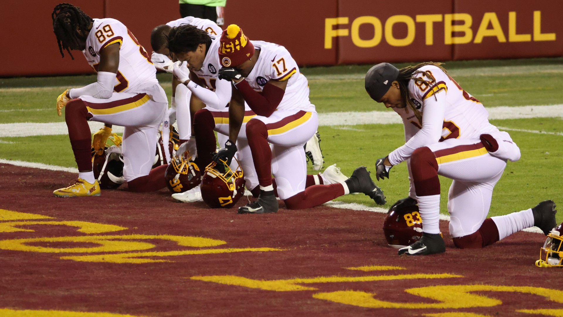 Washington's wide receivers kneel before a game