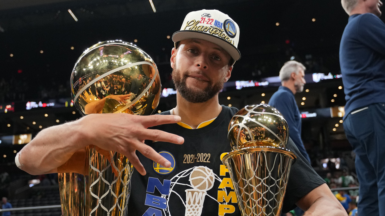 Steph Curry holding trophies after winning the 2022 NBA finals